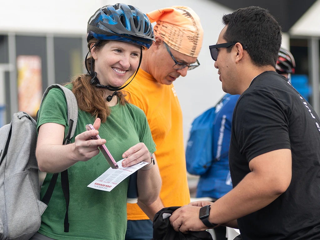 A woman wearing a helmet and holding a pen and a man standing next to him.
