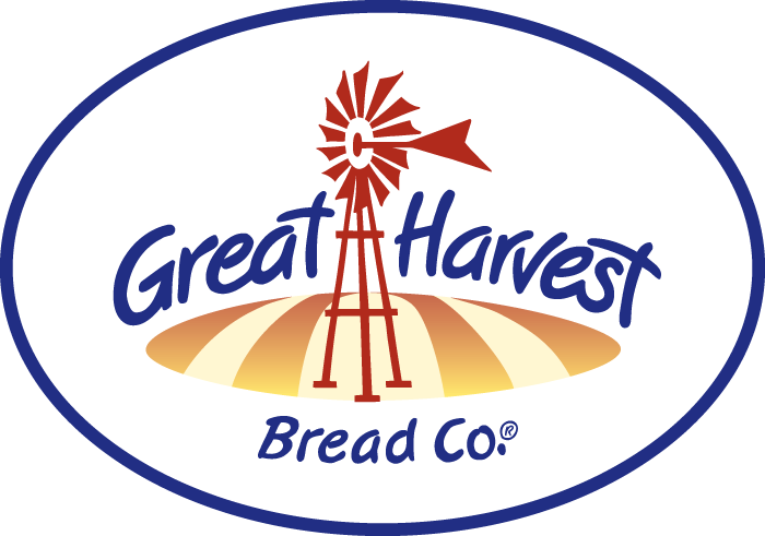 Logo for Great Harvest Bread Co. featuring a red windmill above stylized golden fields, with the company name in blue cursive and print text inside an oval border.